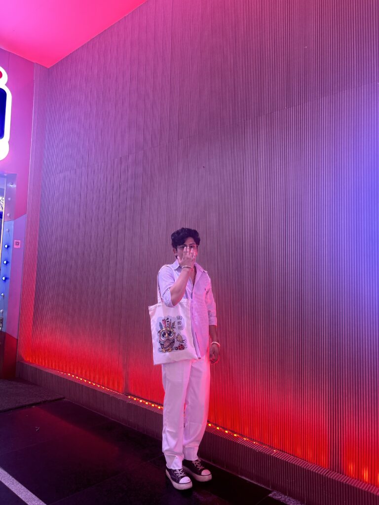Street style photo under neon lights – casual white outfit, tote bag, and sneakers aesthetic – Kapilverse Blog